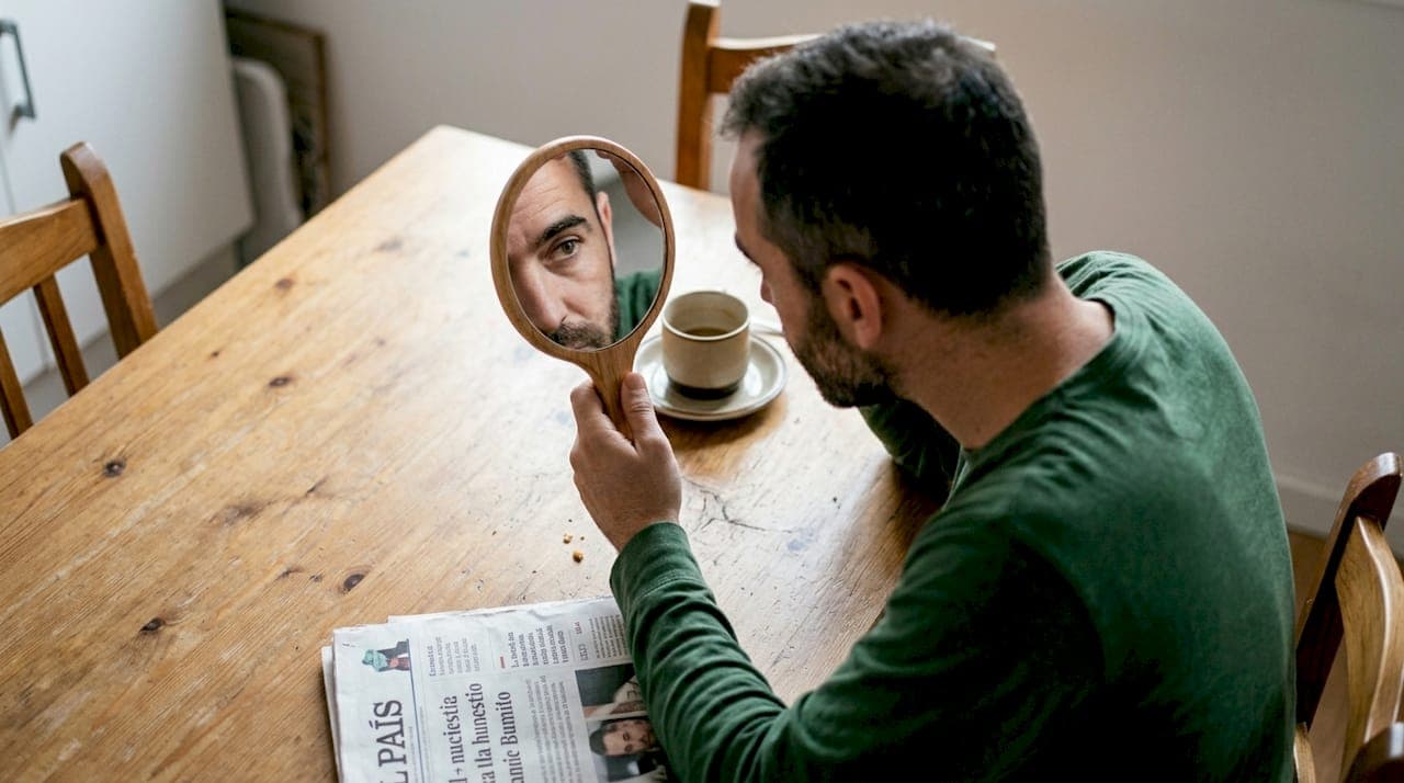Un hombre observa y compara el color de sus cejas con el de su cabello.