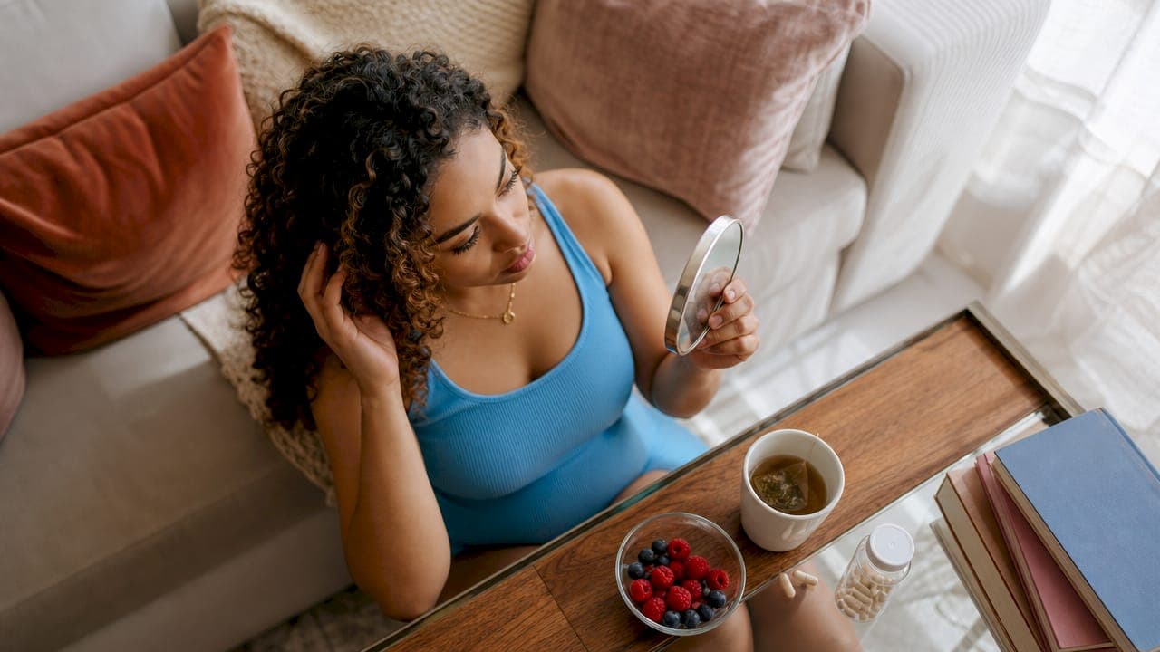New mother examining hair in handheld mirror