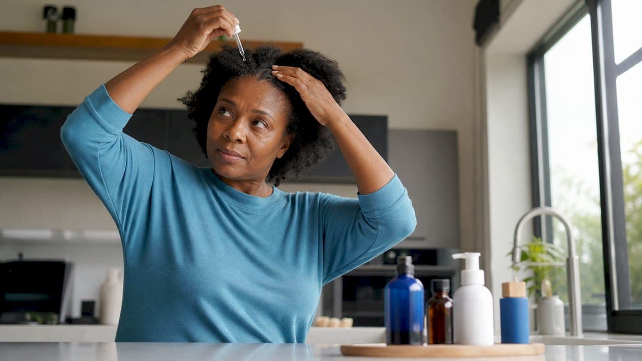 Woman applying scalp treatment at home