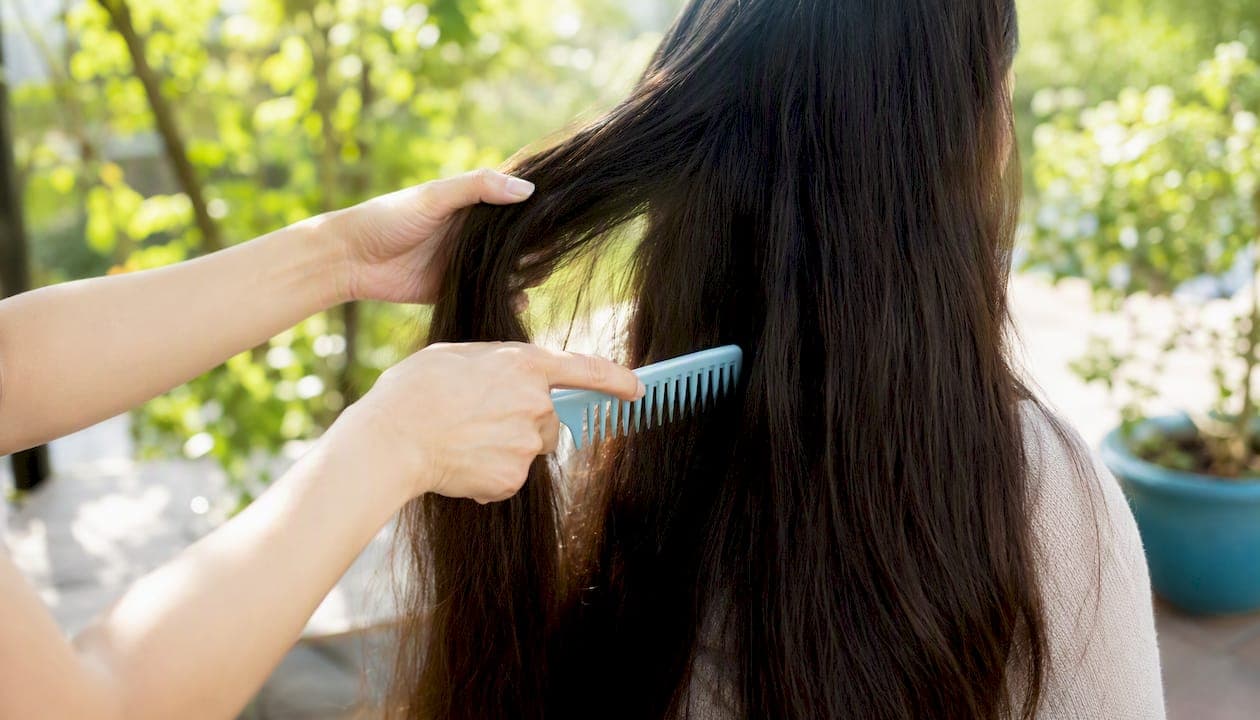Hands gently brushing long hair in morning light