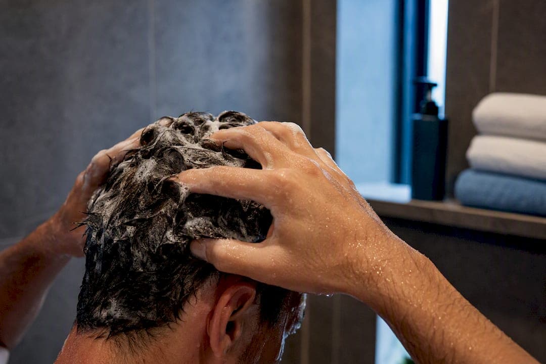 Hands applying shampoo to scalp