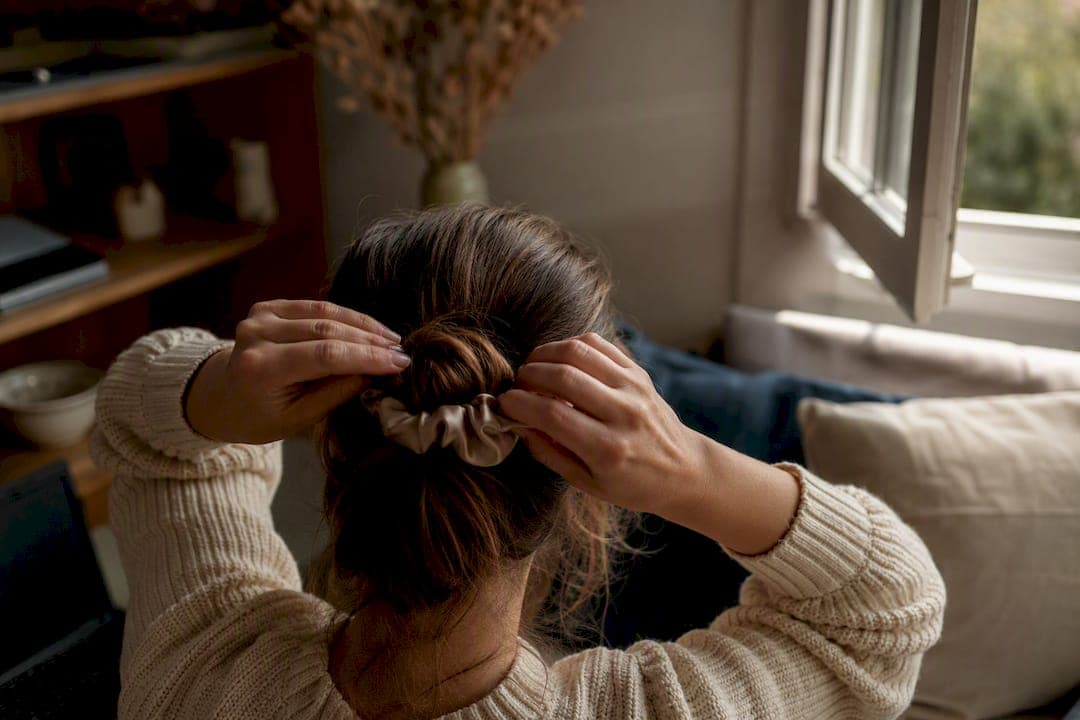 Hands tying hair with silk scrunchie